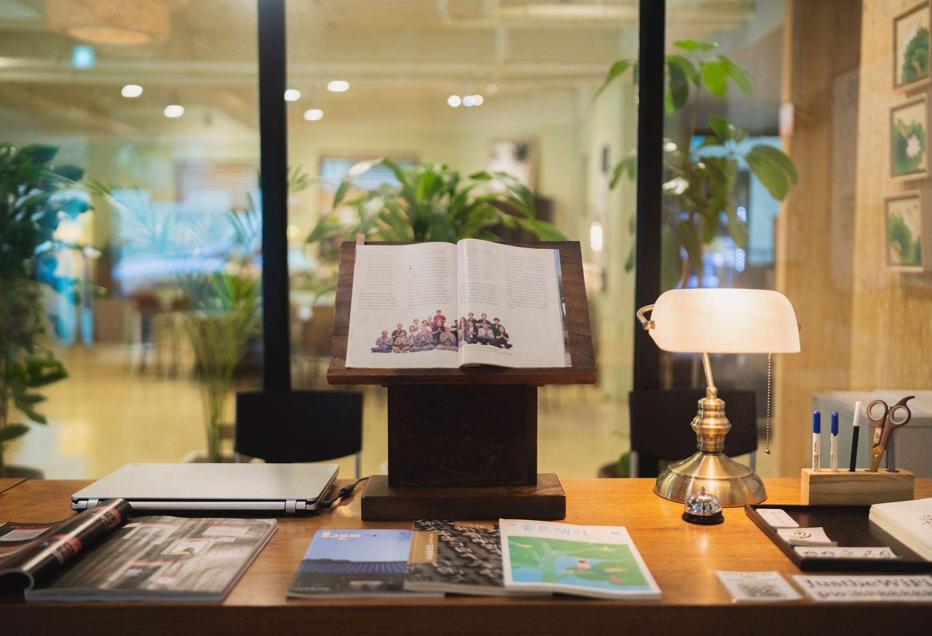 Wooden desk with a music stand holding sheet music, a lamp, and open books.
