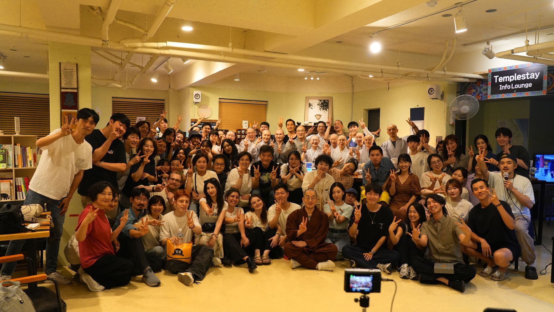 Large group of diverse people smiling, posing together inside a well-lit room.