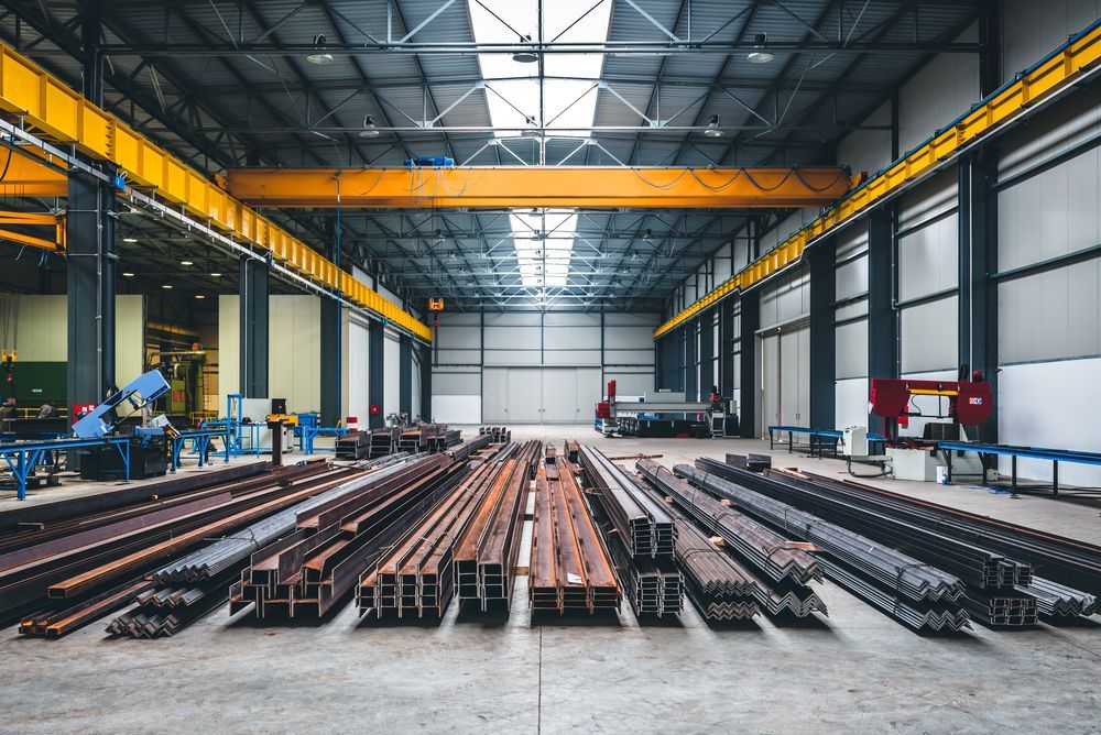 Warehouse interior with steel beams on the floor and yellow overhead cranes — EBS NQ Electronic Building Systems in Kirwan, QLD
