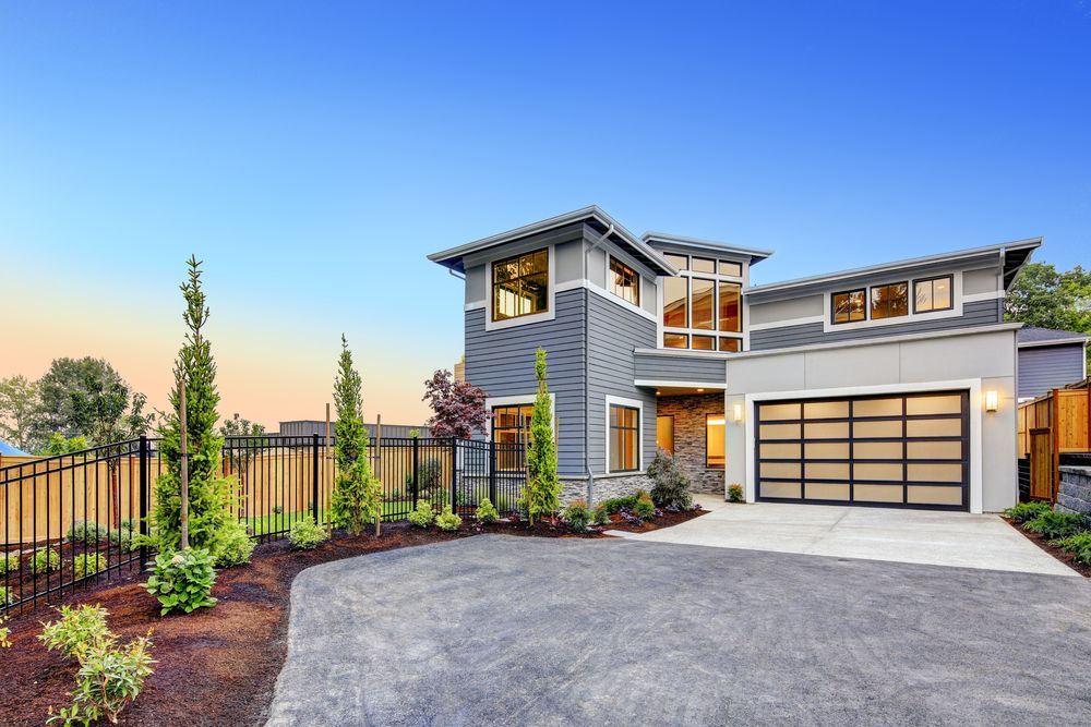 Modern gray house with glass garage door, driveway, and landscaping under a blue sky — EBS NQ Electronic Building Systems in Kirwan, QLD