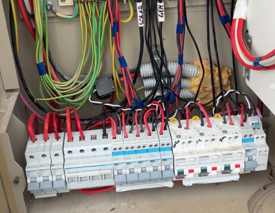 Row of digital electricity meters mounted on a red wall — EBS NQ Electronic Building Systems in Kirwan, QLD