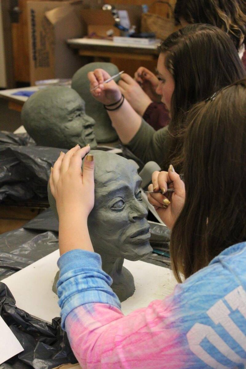 students creating sculptures of heads out of clay