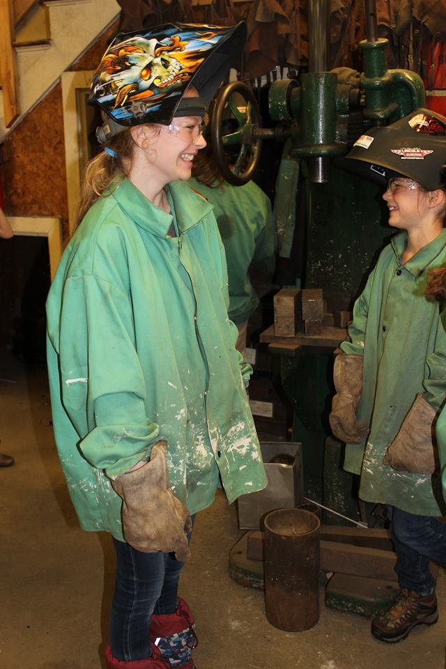 2 girls wearing welding gear laughing