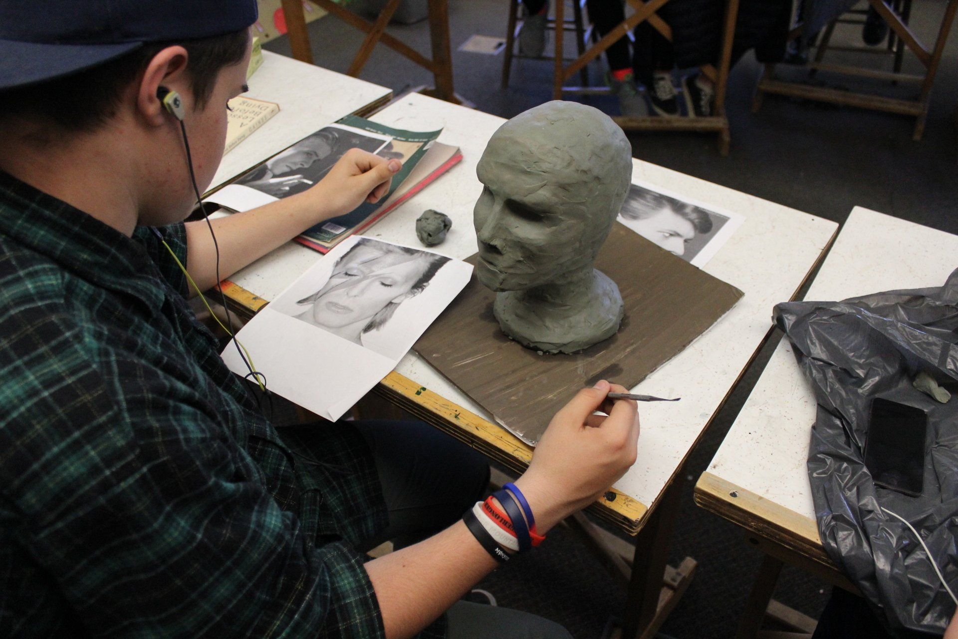 student in a classroom creating a clay scultpure