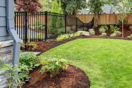 A backyard with a fence and a lush green lawn.