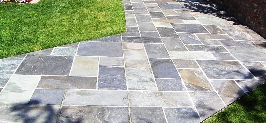Stone tile patio with grass on the sides.