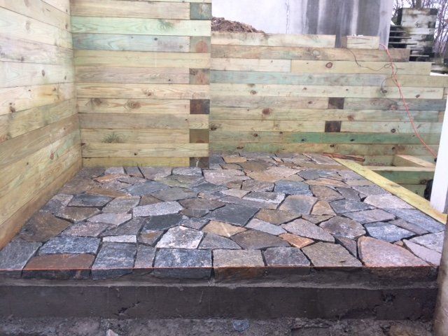 Stone tiled floor with wooden walls being built.