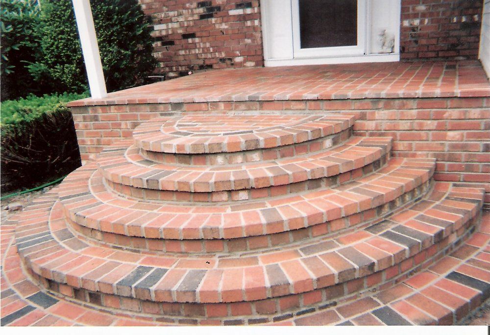 Brick steps leading up to a brick porch with a white-trimmed door.