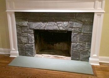 A stone fireplace with a white mantle in a living room.