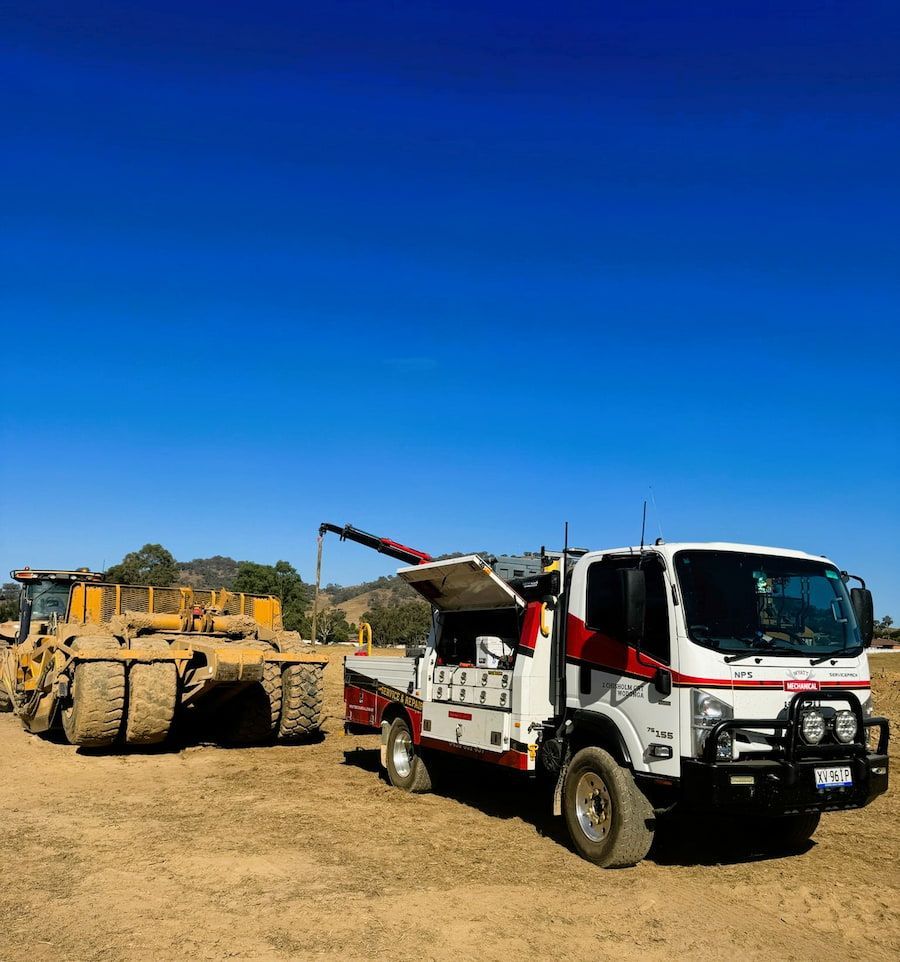 A Tow Truck Is Parked Next To A Bulldozer In A Dirt Field — Wyatt Mechanical Pty Ltd In Wodonga, VIC