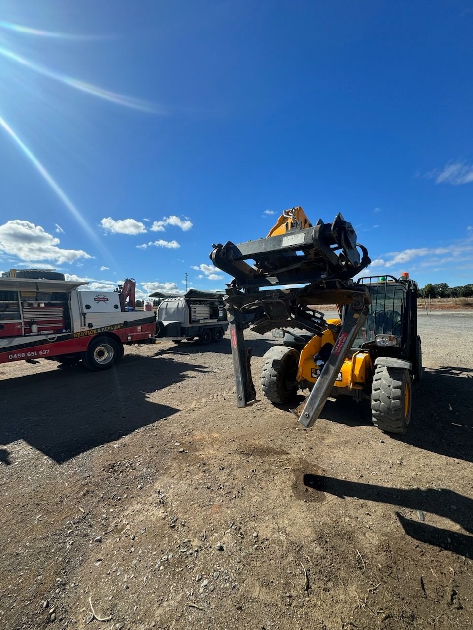A Yellow Bulldozer Next To A Truck With A Mobile Trailer On A Dirt Field — Wyatt Mechanical Pty Ltd In Wodonga, VIC