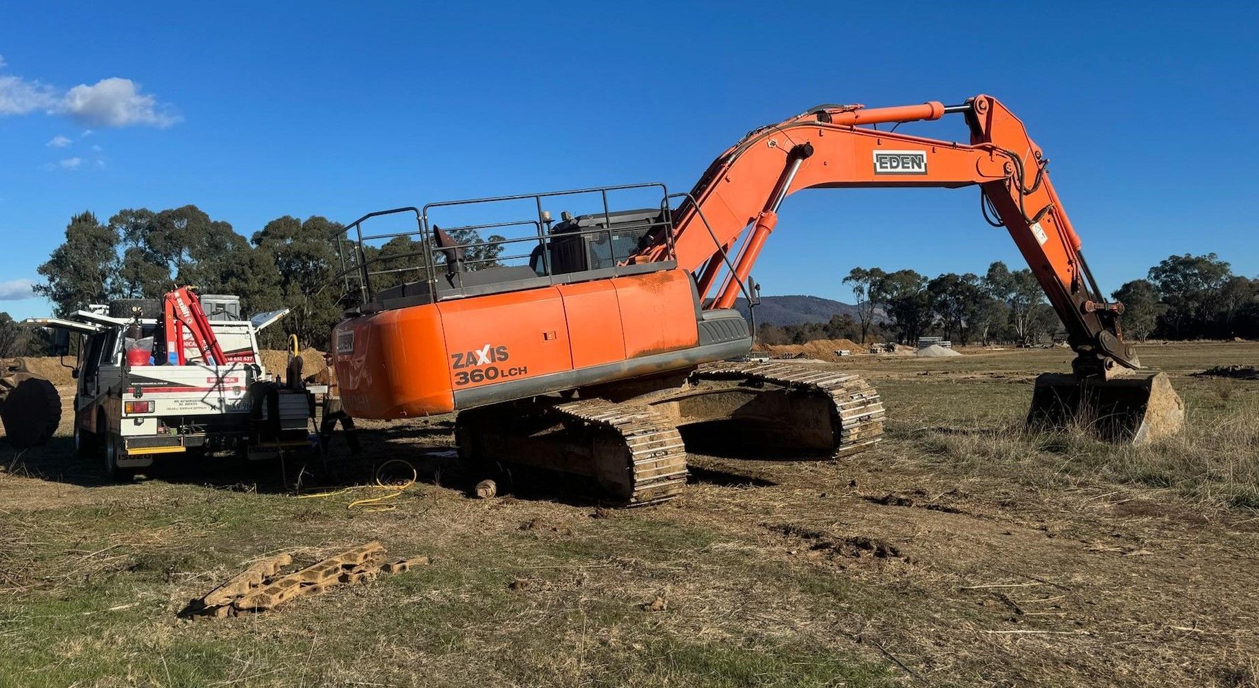 A Large Orange Excavator On A Grass Field — Wyatt Mechanical Pty Ltd In Wodonga, VIC