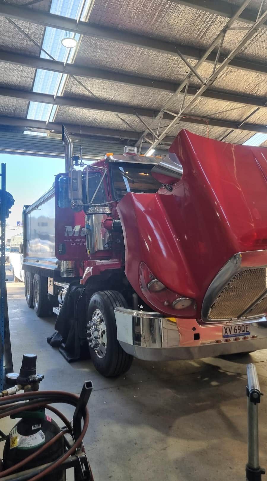 A Red Semi Truck Is Being Worked On In A Garage With The Hood Up — Wyatt Mechanical Pty Ltd In Wodonga, VIC