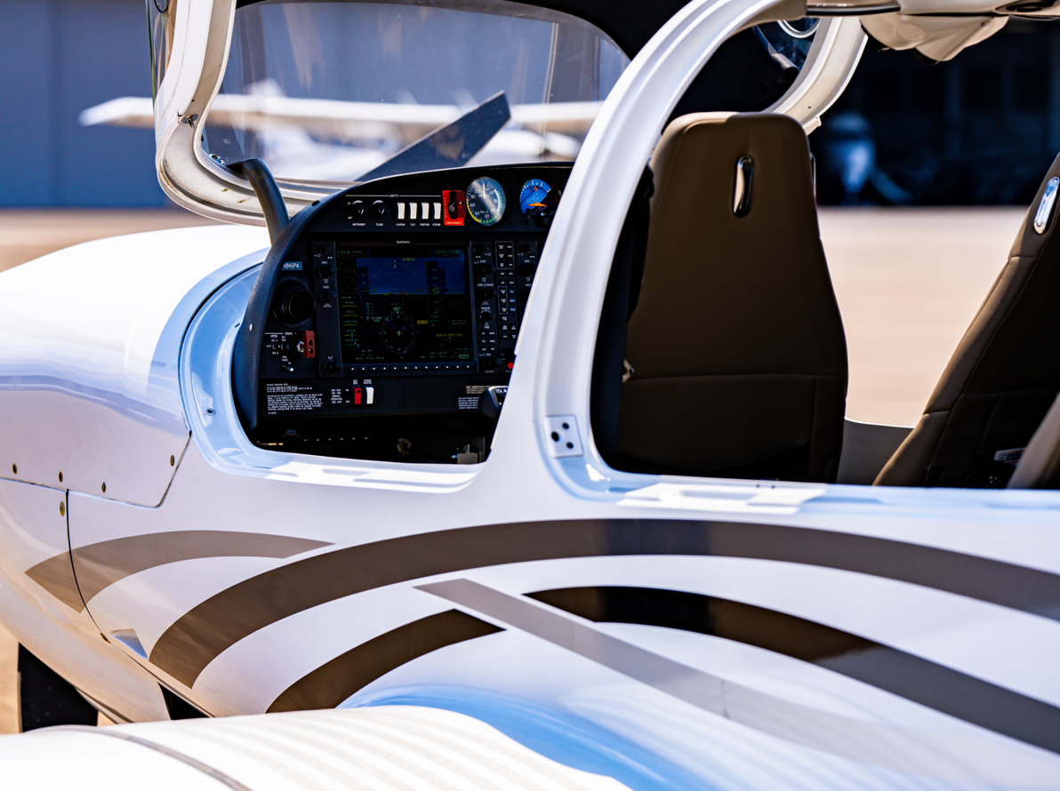 White and black airplane cockpit, dashboard visible, seat, open door.