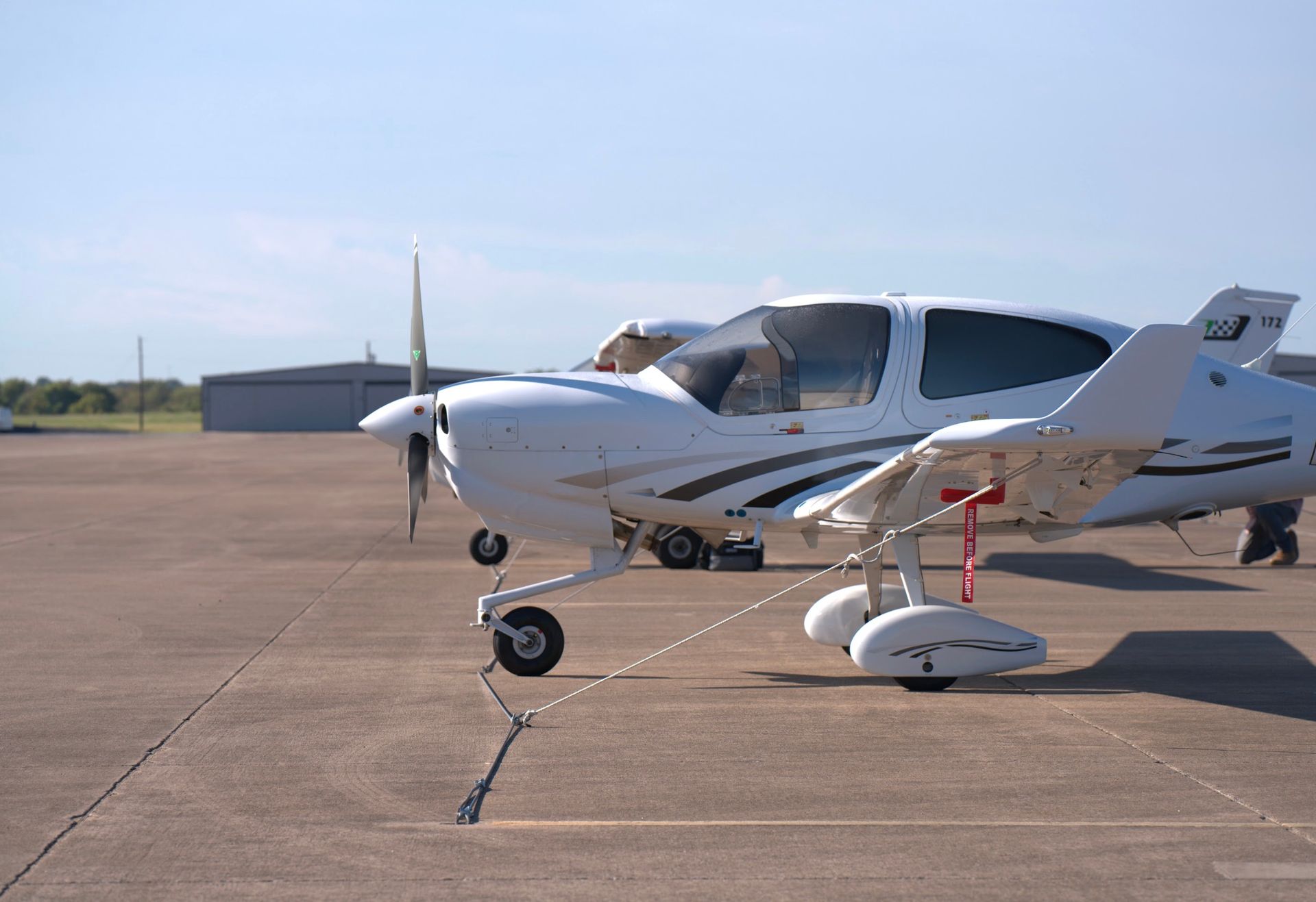 White airplane on a tarmac, near a hangar, under a blue sky.