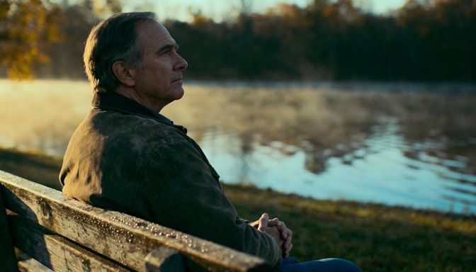 Dayton veteran sitting calmly on a park bench at RiverScape MetroPark morning light reflective and peaceful