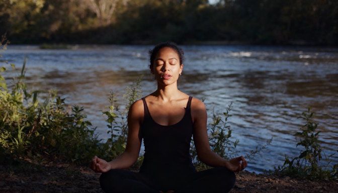 Woman meditating and breathing calmly beside Great Miami River