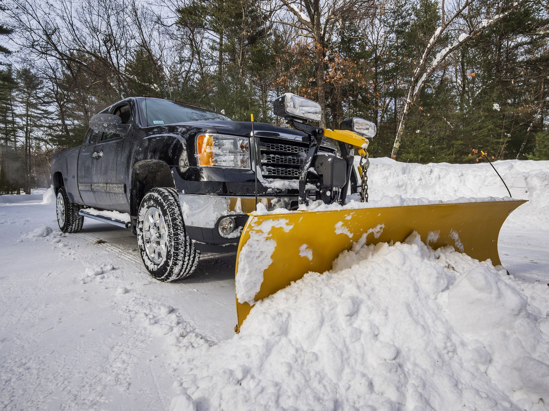 A man is standing next to a snow blower in a parking lot.