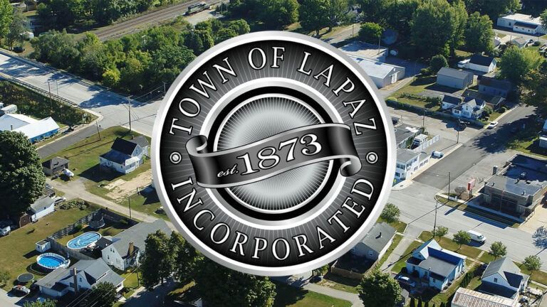 Town of La Paz seal over aerial view of town, including homes and roads.