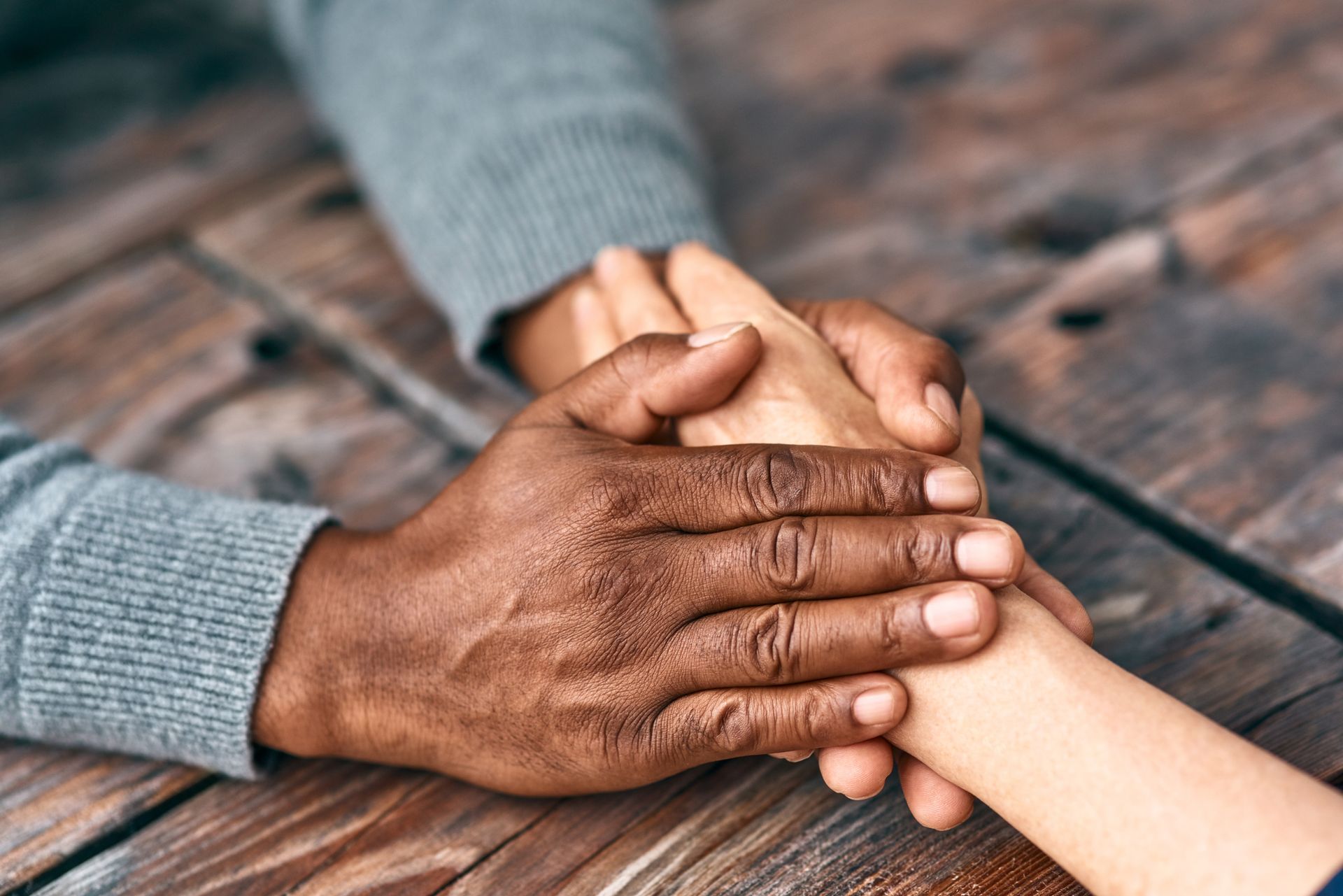 a man and a woman are holding hands on a wooden table .