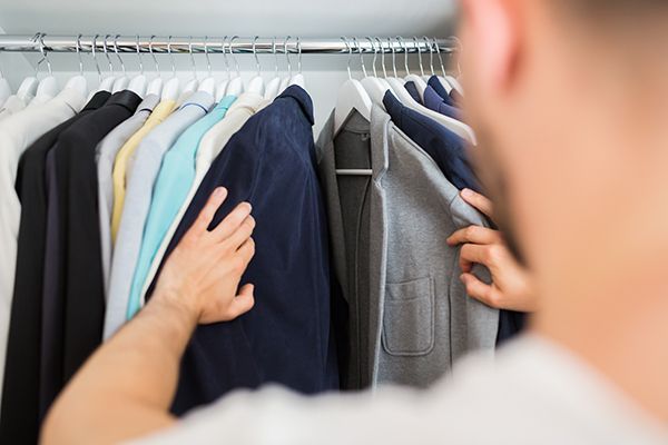 a man is looking at a jacket in a closet .