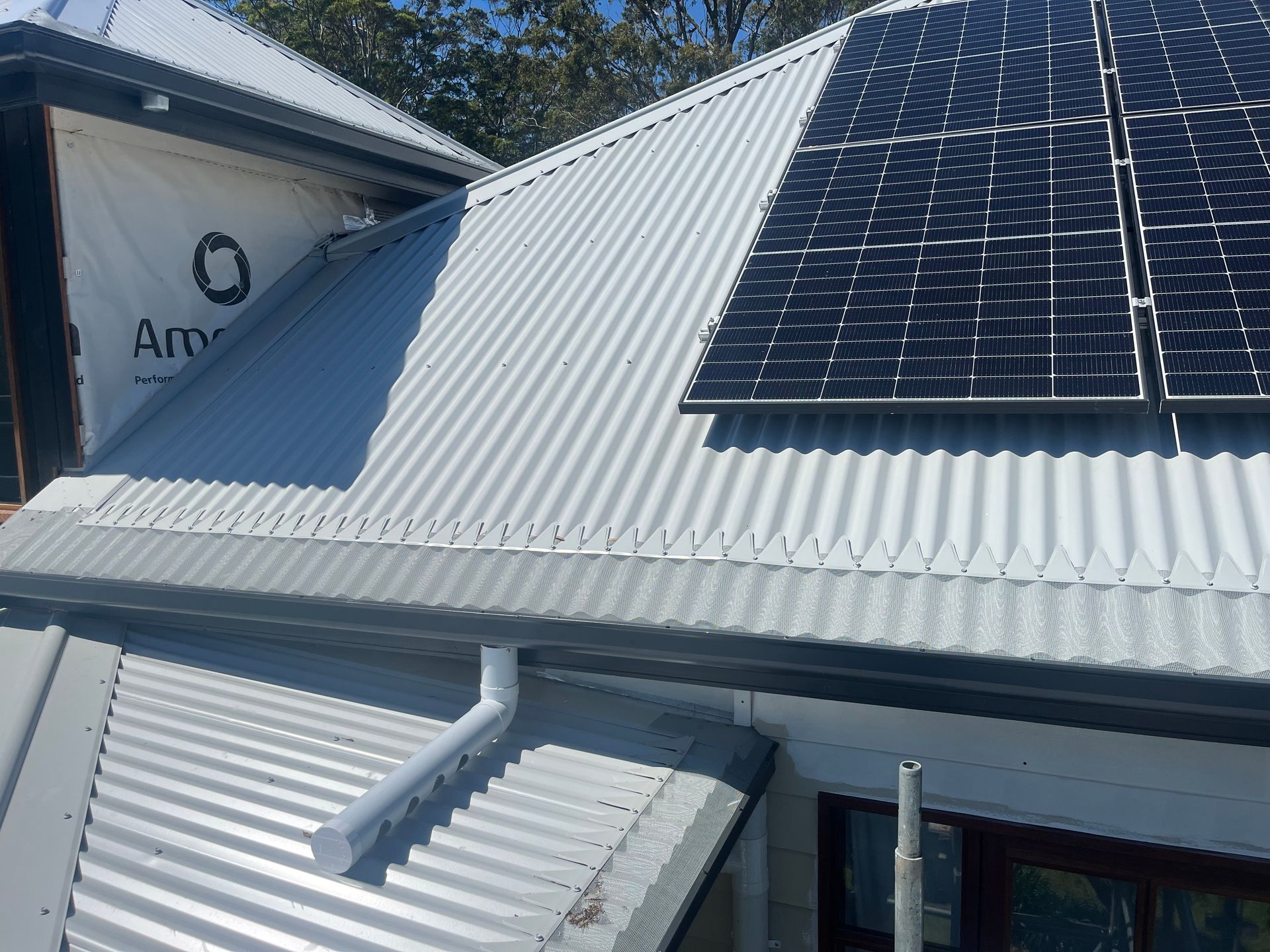 A White Gutter on the Side of a Building With Solar Panels— Metal Roofing by Matt Dwyer in Nowra, NSW