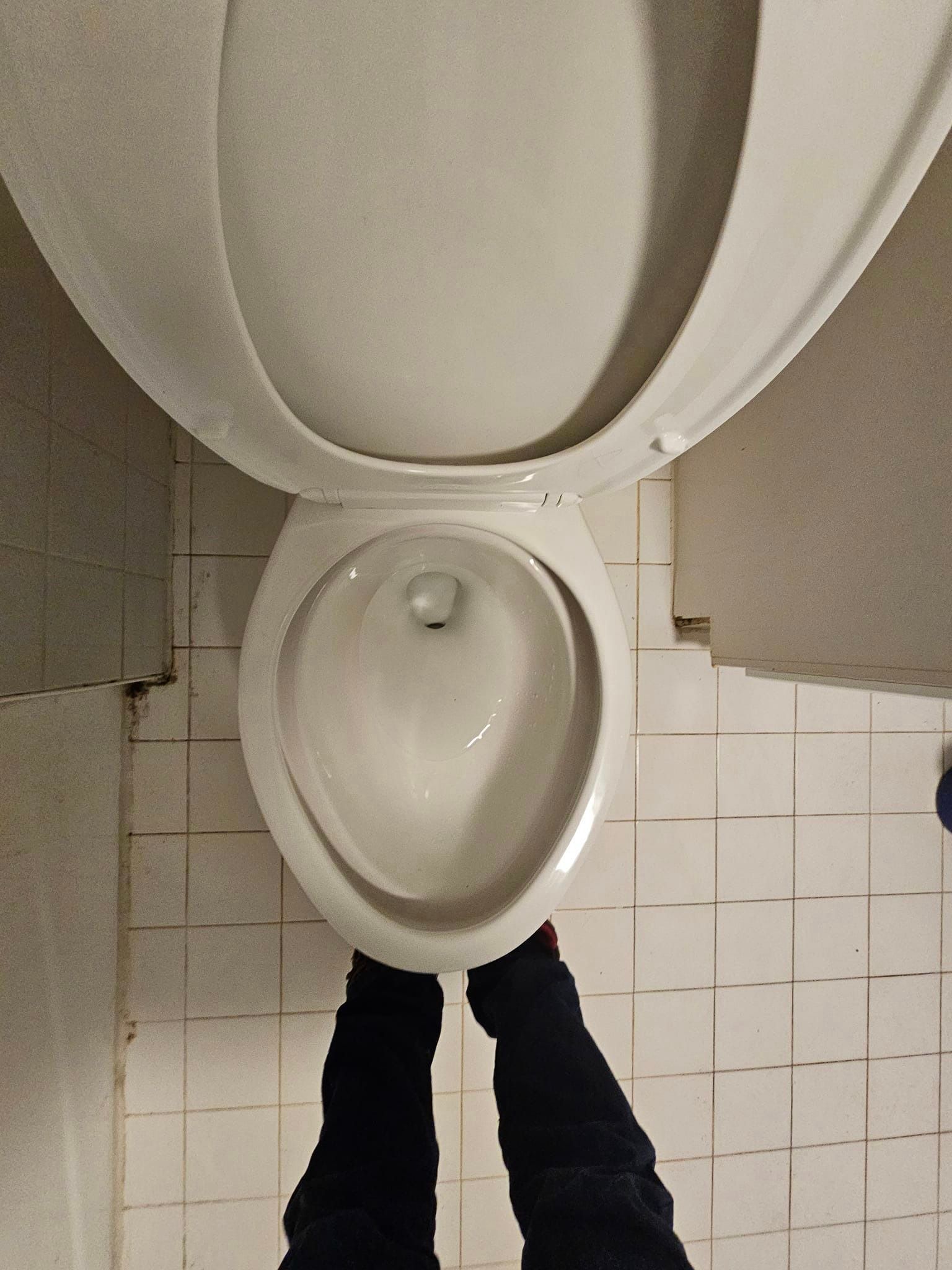A person is standing in front of a white toilet