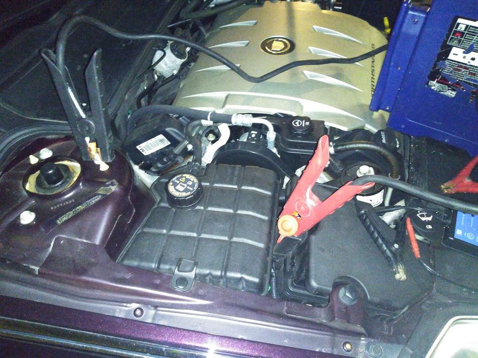 A car engine is being charged with a jump starter