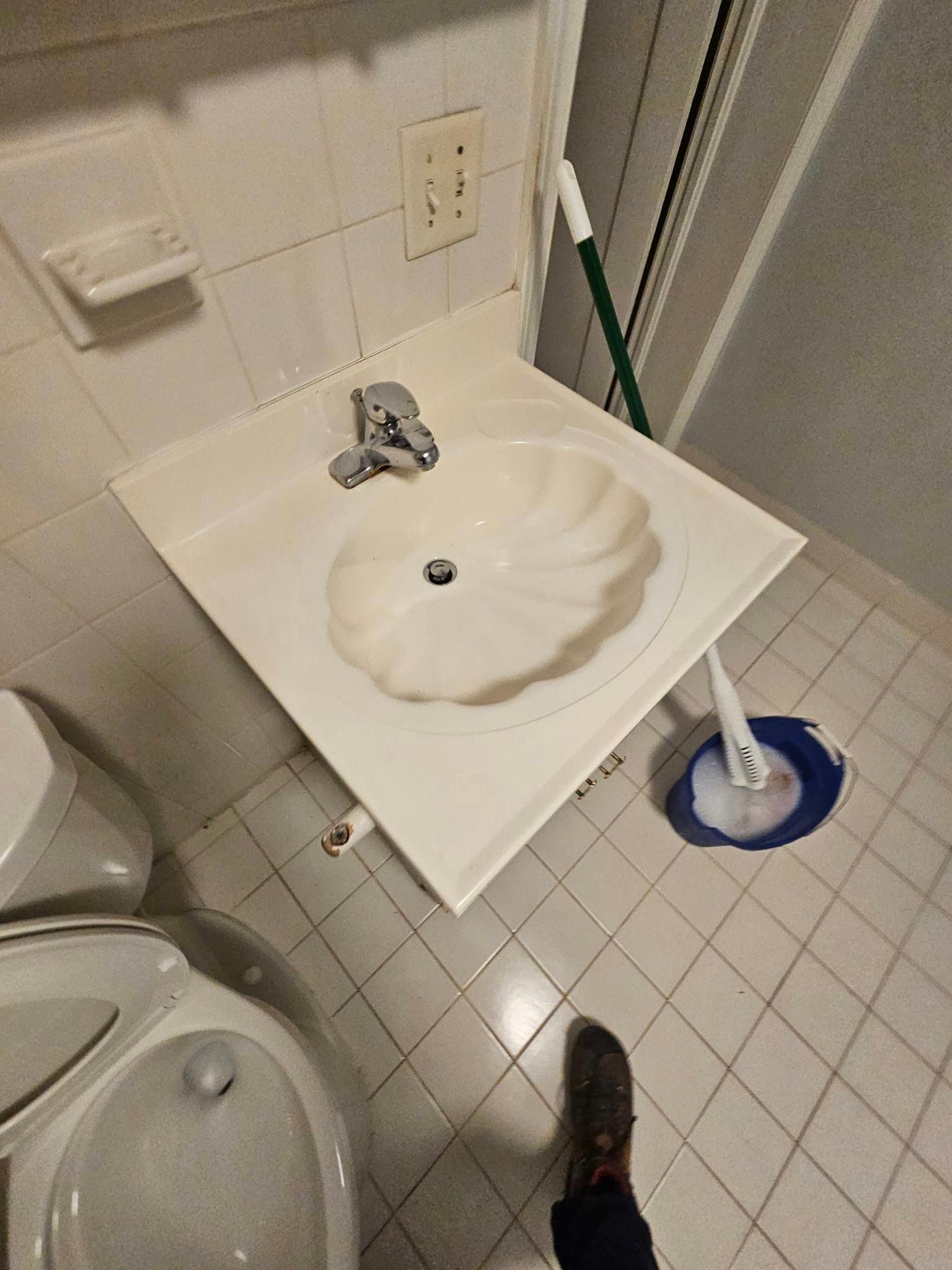 A bathroom with a sink , toilet , and mop.