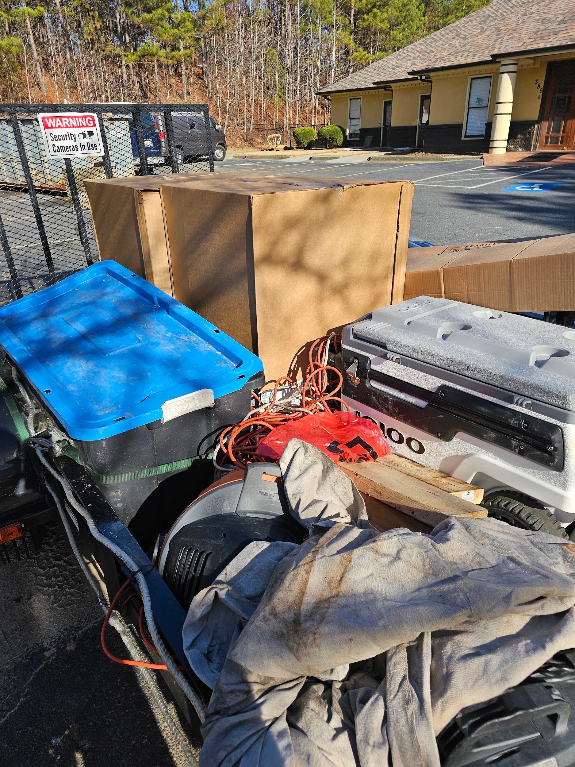 A trailer filled with boxes and tools is parked in front of a building.