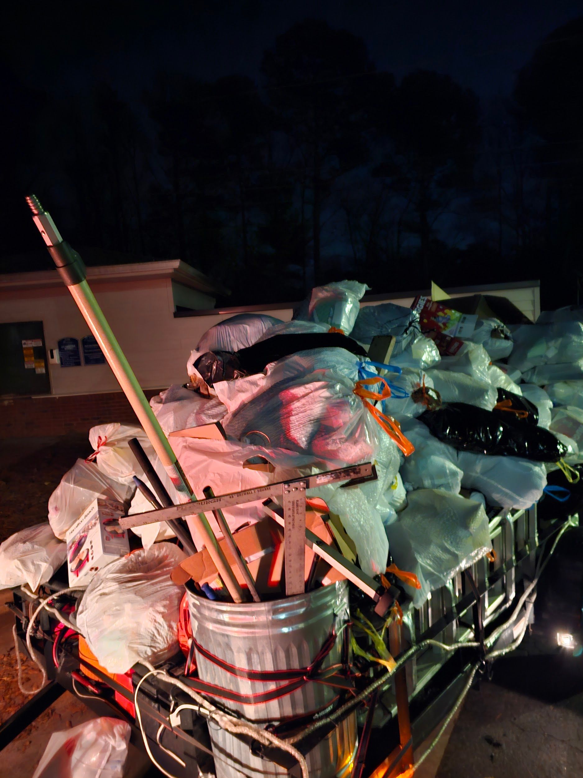 A pile of trash is sitting on top of a trailer at night.