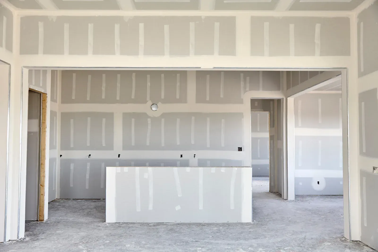 An empty room with drywall on the walls and a counter in the middle.