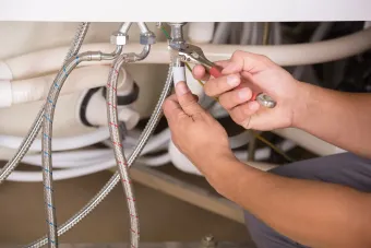 A plumber is fixing a sink with a pair of pliers.