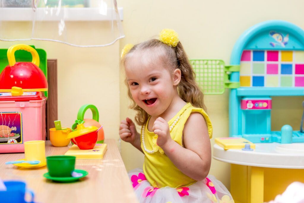 A young girl with down syndrome plays with plastic food and dishes in montessori special education