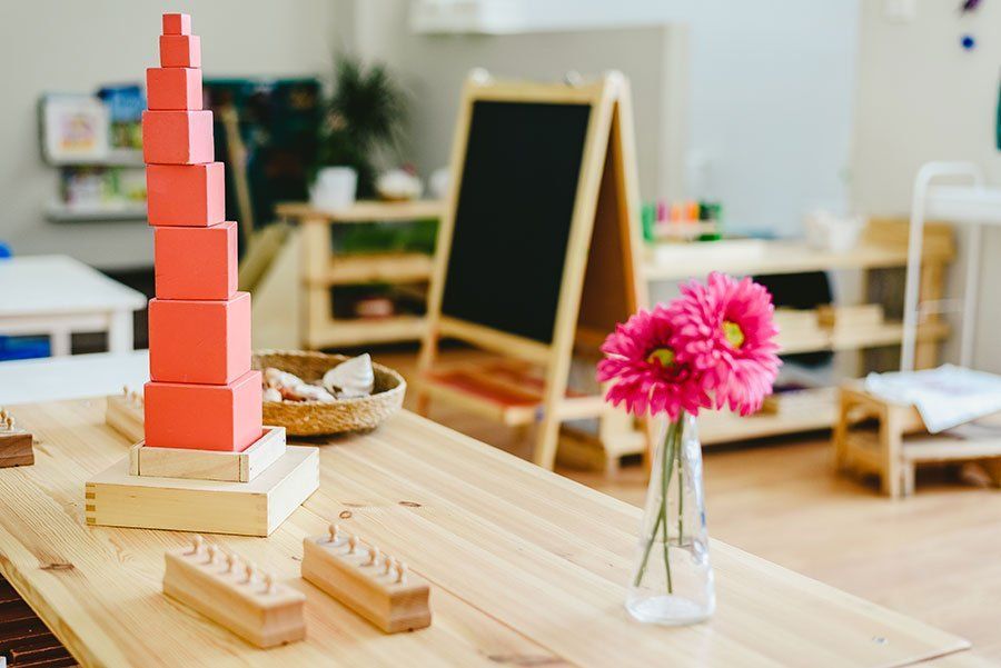 A wooden table with toys and a vase of flowers on it.