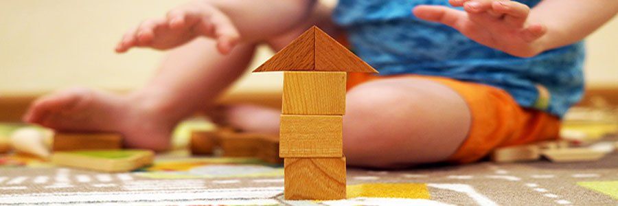 A child is sitting on the floor playing with wooden blocks.