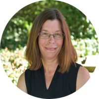 A woman wearing glasses and a black shirt smiles for the camera