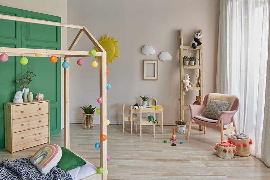 A child 's room with a bed , dresser , chair , table and toys.