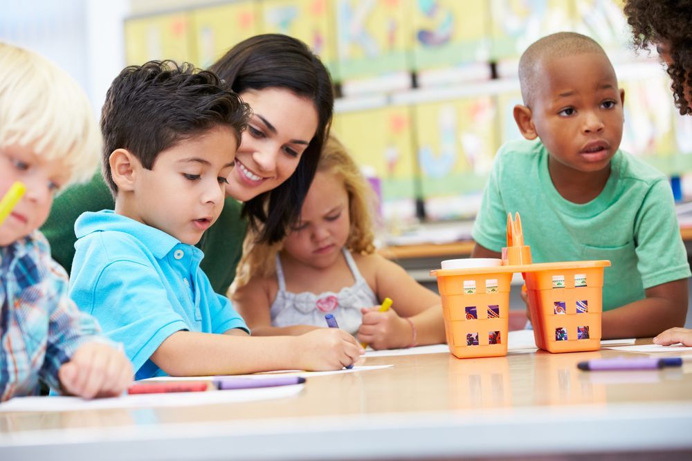 Monetessori teacher helping students in a multi age classroom