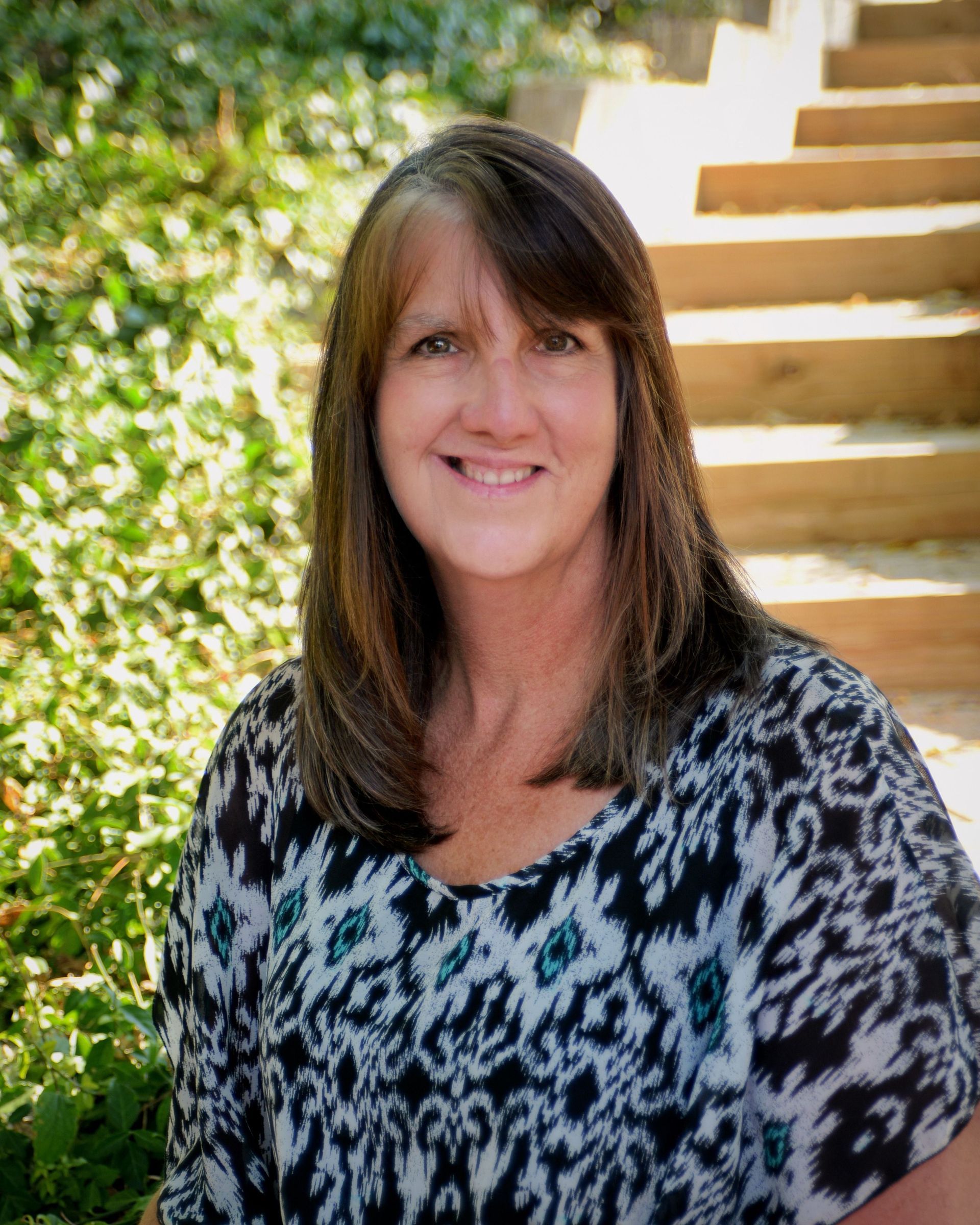 A woman in a blue shirt is smiling for the camera