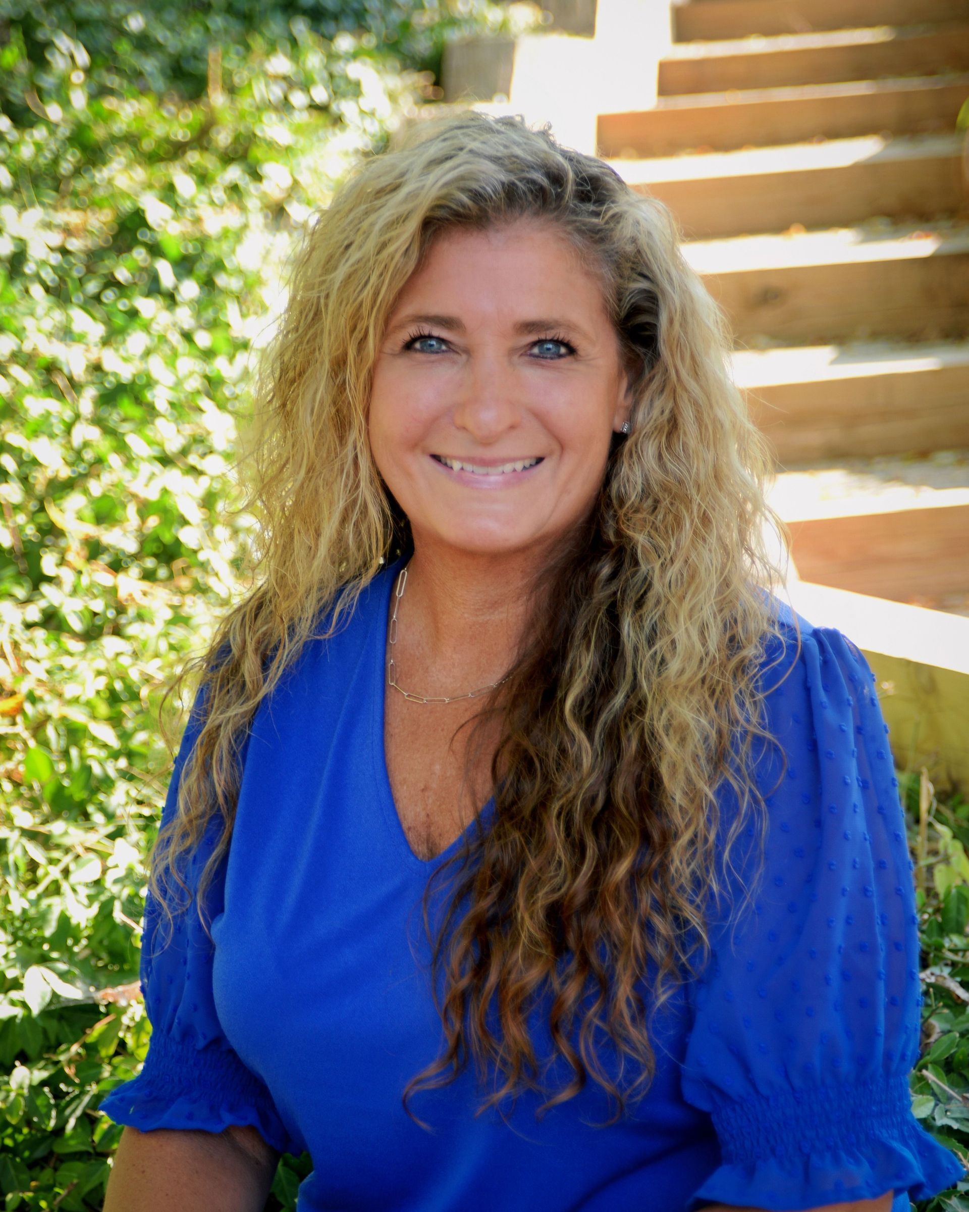 A woman with long curly hair is smiling in a circle.