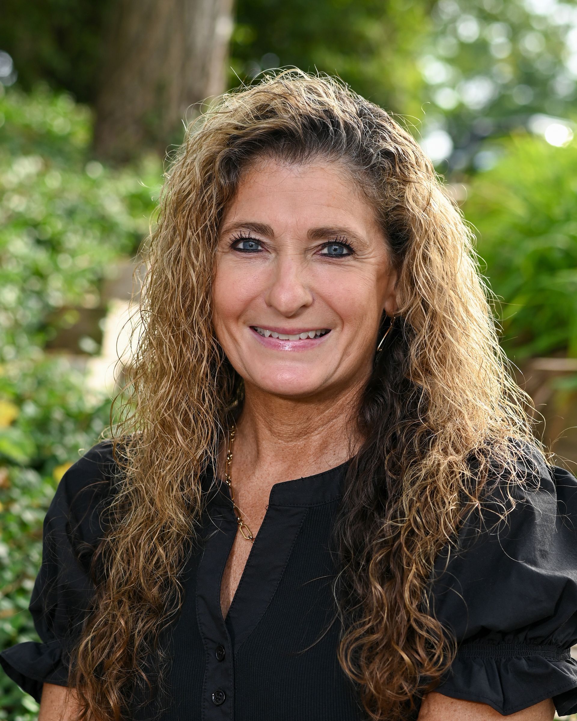 A woman with long curly hair is smiling in a circle.