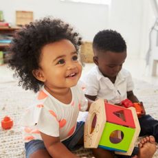 A boy and a girl are sitting on the floor playing with toys