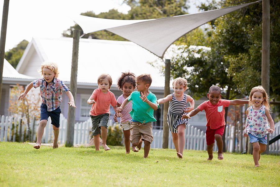 A group of children are running in the grass holding hands.