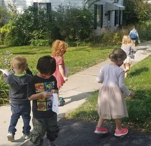 A group of children are walking down a sidewalk.