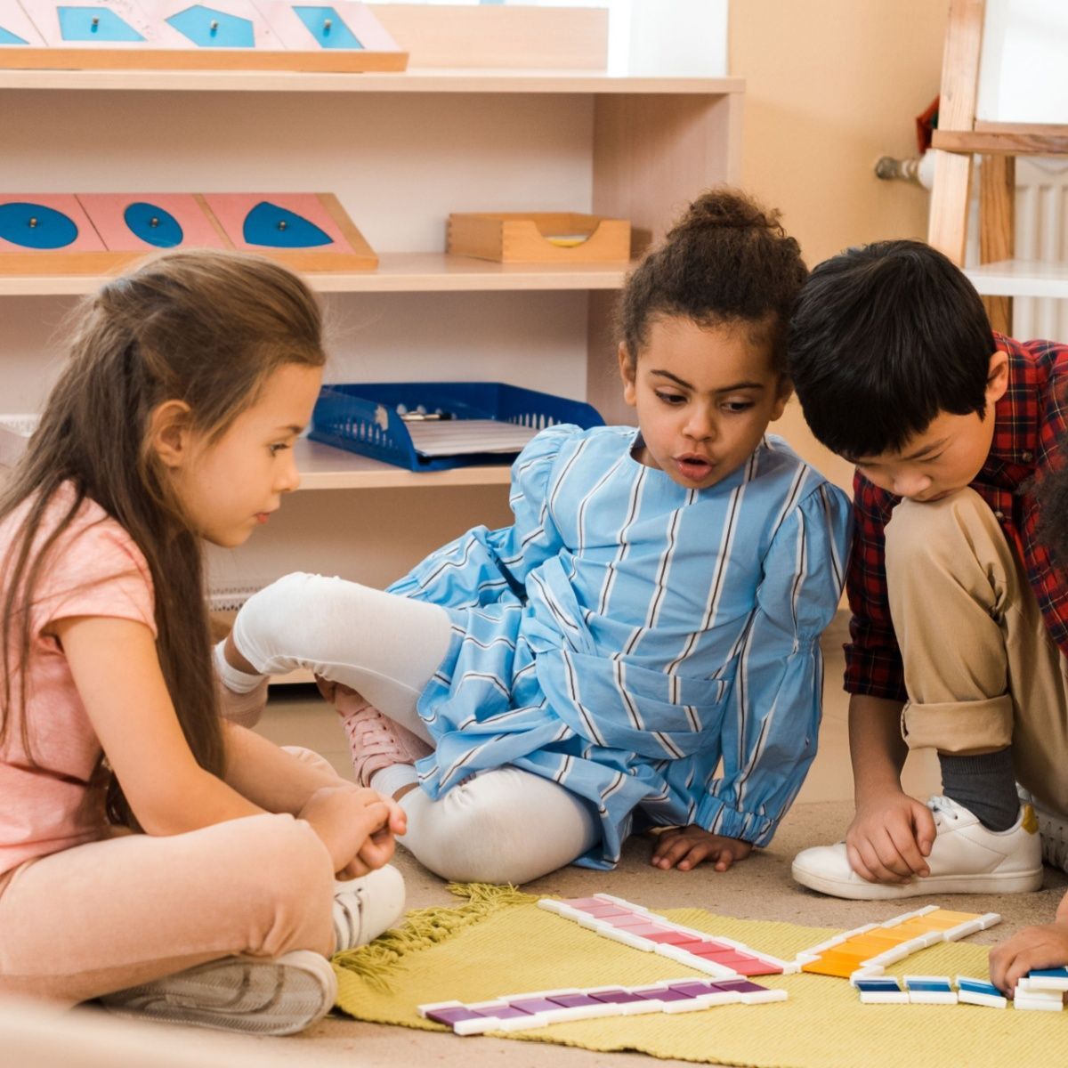 A group of children are sitting on the floor playing with toys.