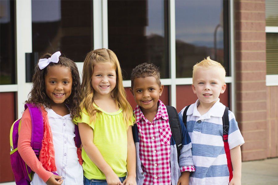 A group of children are posing for a picture in front of a school building.