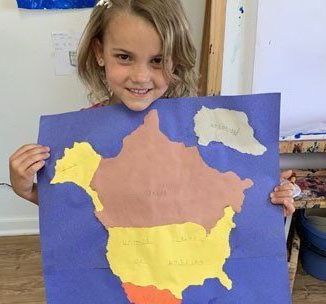 A young girl is holding a piece of paper with a map of the united states on it.