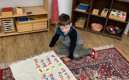 A young boy is sitting on the floor playing with a rug.