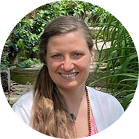 A woman is smiling in a circle with plants in the background.